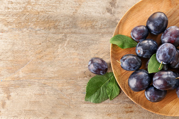 Fresh ripe plums on wooden plate