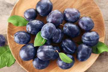 Fresh ripe plums on wooden plate