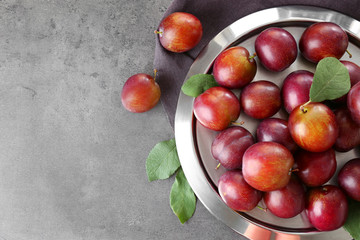 Metal tray with ripe plums on table