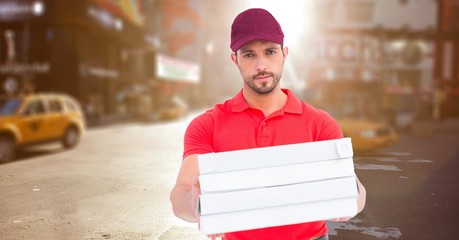 Delivery man with pizza boxes against blurry street with flare