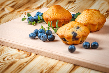 Blueberry muffin. Homemade baked cupcake with blueberries, fresh berries, mint on wooden background. Empty space for text.