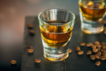 Cognac or liqueur, coffee beans and spices on a glass table.