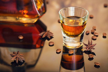 Cognac or liqueur, coffee beans and spices on a glass table.