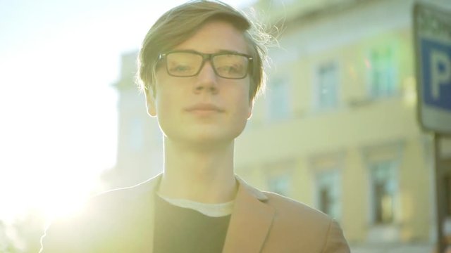 closeup attractive smarty guy with glasses looking at camera on warm sunny day slow motion 