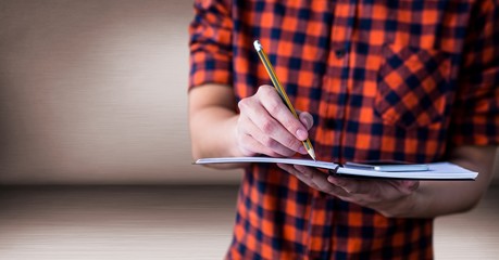 Millennial man mid section with notepad in pink room