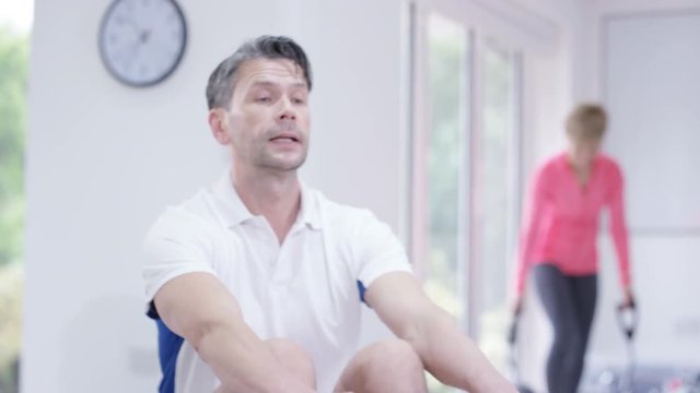  Healthy active mature man working out on rowing machine at the gym