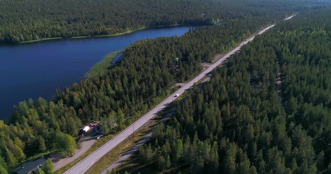 Car on autumn color road, Cinema 4k aerial view following a car driving between lake pyhajarvi and pyhatunturi, in the arctic taiga wilderess of Lapland, in Lappi, Finland