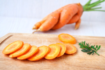 Raw carrots whole and sliced on a wooden board