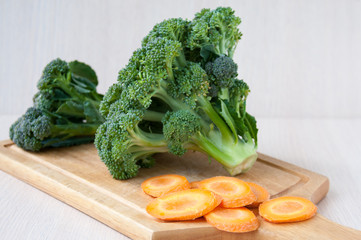 Raw carrot sliced and broccoli on a wooden board