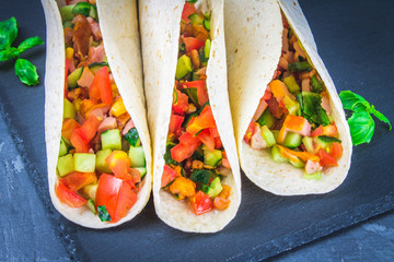 Traditional Mexican tacos with meat and vegetables on wooden background
