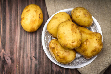 Raw potatoes on a brown wooden background