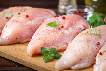 Raw chicken fillets on a cutting board against the background of a wooden table. Meat ingredients for cooking.