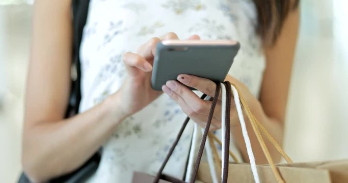 Woman use of smart phone and holding carry paper bags