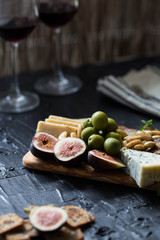 Beautiful Date Night Cheese Board with Cheddar Manchego and Blue Cheese Prosciutto Almonds and Olives on Wooden with Two Wine Glasses
