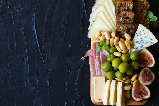 Beautiful Date Night Cheese Board with Cheddar Manchego and Blue Cheese Prosciutto Almonds and Olives on Slate Background Copy Space - Powered by Adobe