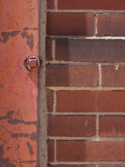 Close-up of a brick wall with red rusted metal beam