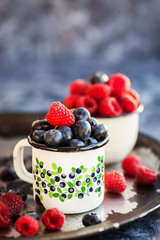 Fresh ripe blueberry and raspberry in mugs