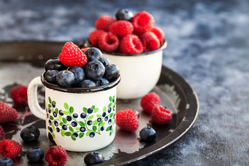 Fresh ripe blueberry and raspberry in mugs