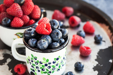 Fresh ripe blueberry and raspberry in mugs