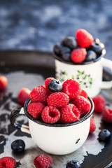 Fresh ripe blueberry and raspberry in mugs