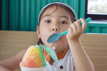 little girl eating rainbow snow cone in summer