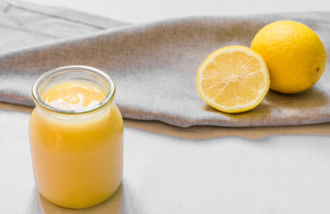 Lemon curd cream in a glass jar against white background