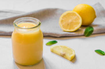Lemon curd cream in a glass jar against white background