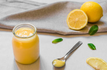 Lemon curd cream in a glass jar against white background