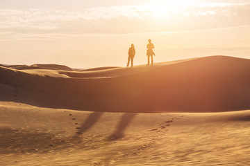 Two human silhouettes in the sand desert 