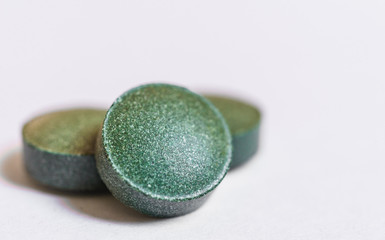 Spirulina pills tablets macro photo against white background. Dietary supplement, superfood, fitness, and healthy eating concept.