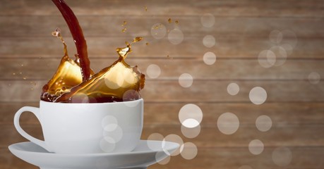 Coffee being poured into white cup with bokeh against blurry