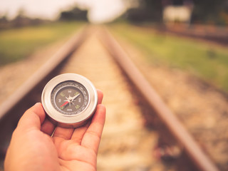 Vacation and travel concept.  Retro hand holding  compass on railway background with copy space on top.