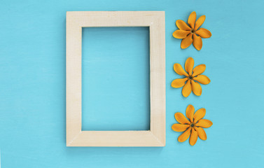Wooden frame with yellow flower on blue background