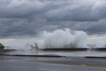 Large Waves on the Malecon, Old Havana, Cuba, with 3 people running for safety.