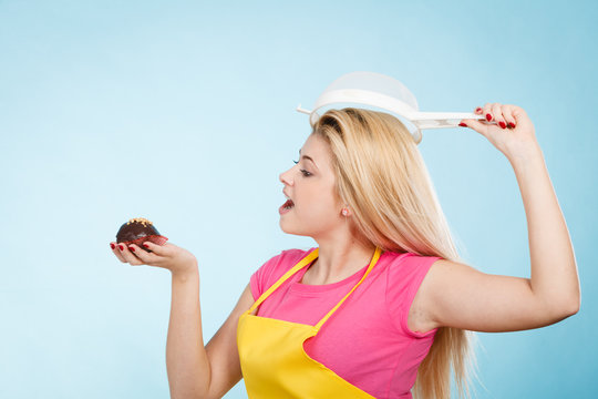 Woman holding cupcake wearing colander on head
