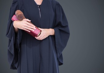 Female judge mid section with book and gavel against grey