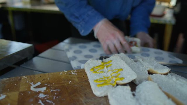  Street food vendor making hot dogs for customers at summer festival