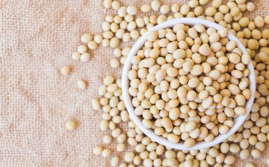 Closeup top view soy beans on white bowl with sackcloth background , healthy food concept