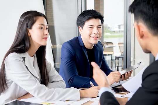 Young asian businessman and Businesswoman discussing in the meeting in office cafe, brain storming for business strategy with happy feeling and smile