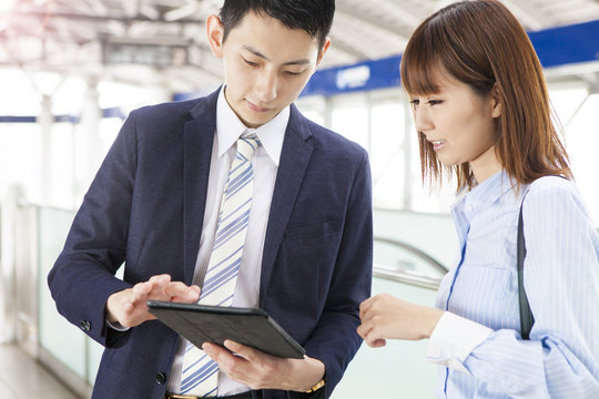 Business couple speaks while using tablet at the station home