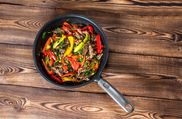 Stir frying beef with sweet peppers and green beans. Top view