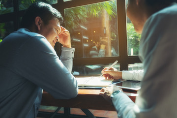 A picture of a business man sitting at a cafe talking in the afternoon of a bright day.