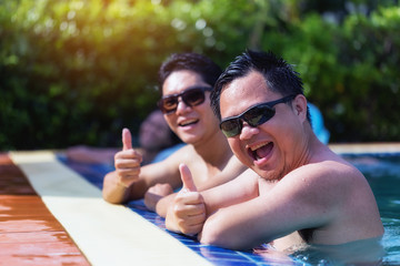 Portrait of a businessman with a thumbs up showing admiration while relaxing by the pool.