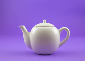 White teapot on purple background.