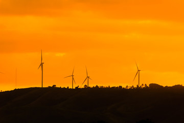 Wind turbines for electricity on a mountain at sunset.