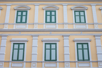 Fototapeta na wymiar Green Windows on Yellow Vintage wall Pattern and wallpaper has architecture in Bangkok Thailand.