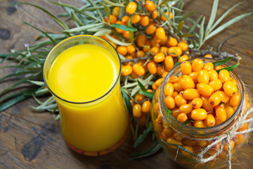 стакан свежего сока из ягод облепихи и ягоды на ветке