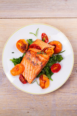 Salmon fillet with spinach, tomatoes and herbs. View from above, top studio shot, vertical