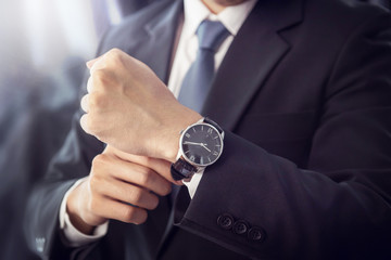 closeup watch on hand businessman, he checking time on watch, dark tone.