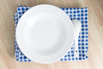 White empty plate with fork and spoon on wooden table